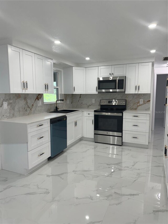 kitchen with backsplash, sink, stainless steel appliances, and white cabinets