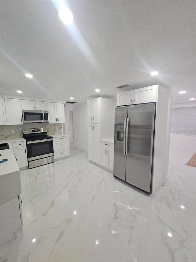 kitchen featuring white cabinetry, a textured ceiling, appliances with stainless steel finishes, and backsplash