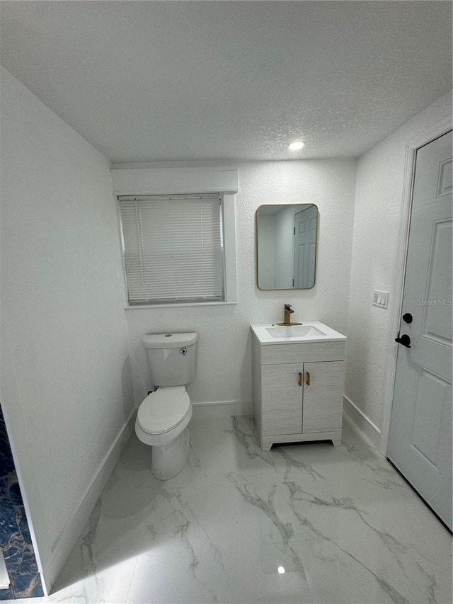 bathroom with a textured ceiling, vanity, and toilet