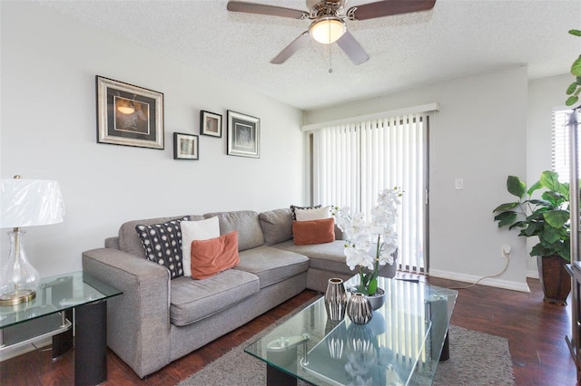 living room featuring dark wood-type flooring, ceiling fan, and a textured ceiling