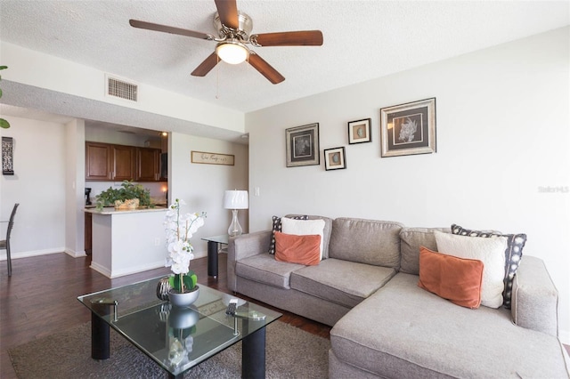 living room with a textured ceiling, ceiling fan, and dark hardwood / wood-style floors