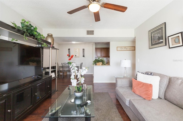 living room featuring a textured ceiling, ceiling fan, and dark hardwood / wood-style floors