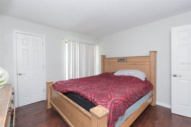 bedroom with a textured ceiling and dark hardwood / wood-style floors