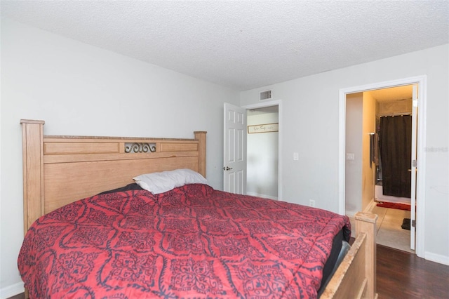 bedroom with a textured ceiling and dark hardwood / wood-style floors