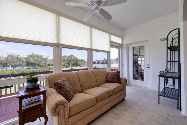 living room featuring light wood-type flooring, a textured ceiling, a water view, and ceiling fan