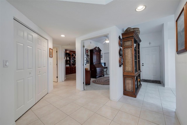 hallway with a textured ceiling and light tile patterned flooring