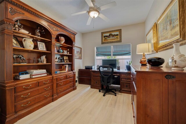 home office featuring built in desk, ceiling fan, and light hardwood / wood-style floors