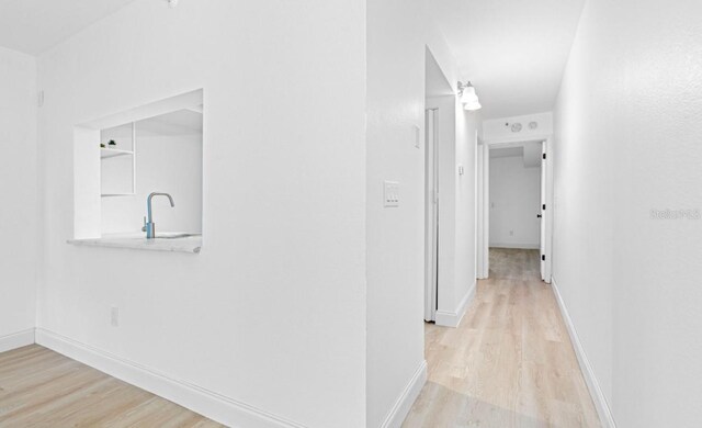 hallway with sink and light wood-type flooring