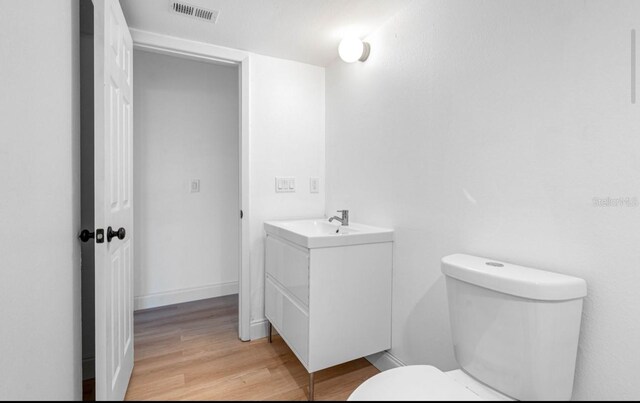 bathroom with wood-type flooring, toilet, and vanity