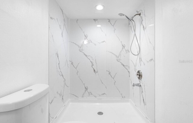 bathroom featuring tiled shower and toilet