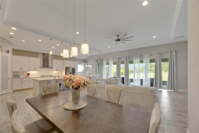 dining room with ceiling fan with notable chandelier, a healthy amount of sunlight, and light hardwood / wood-style flooring