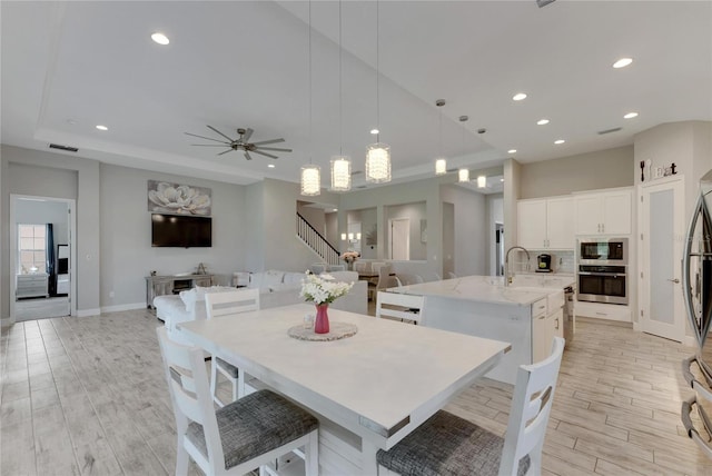 dining area with light hardwood / wood-style flooring, sink, and ceiling fan