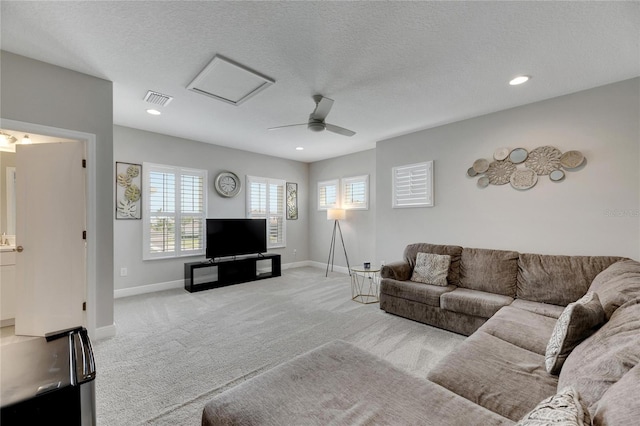 living room featuring a textured ceiling, ceiling fan, and light carpet