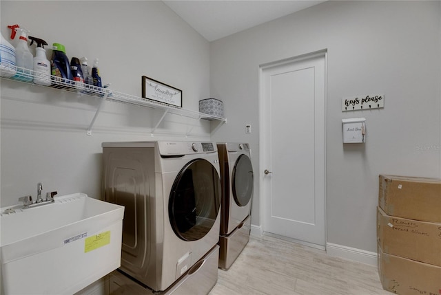 washroom featuring light wood-type flooring, washing machine and dryer, and sink