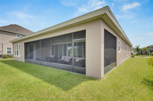 rear view of property featuring a lawn and a sunroom