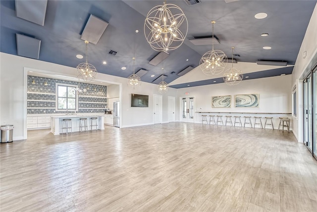 unfurnished living room with vaulted ceiling, a chandelier, and wood-type flooring