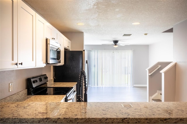 kitchen featuring white cabinets, light stone countertops, stainless steel appliances, a textured ceiling, and ceiling fan