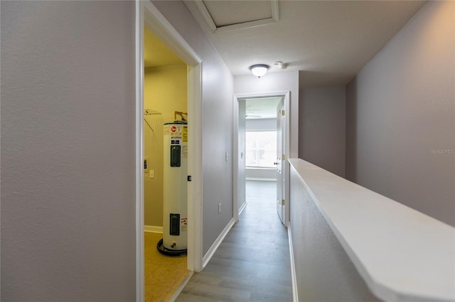 hall featuring water heater, light hardwood / wood-style flooring, and a textured ceiling