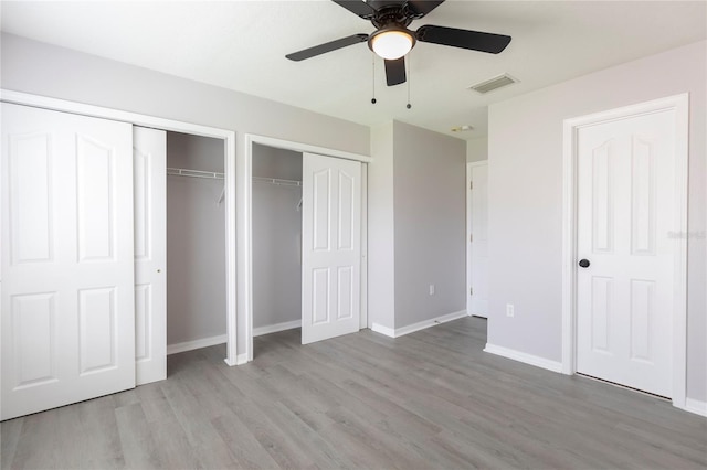 unfurnished bedroom featuring ceiling fan, multiple closets, and light hardwood / wood-style flooring