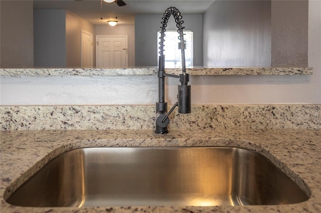 interior details featuring light stone counters, decorative light fixtures, sink, and ceiling fan