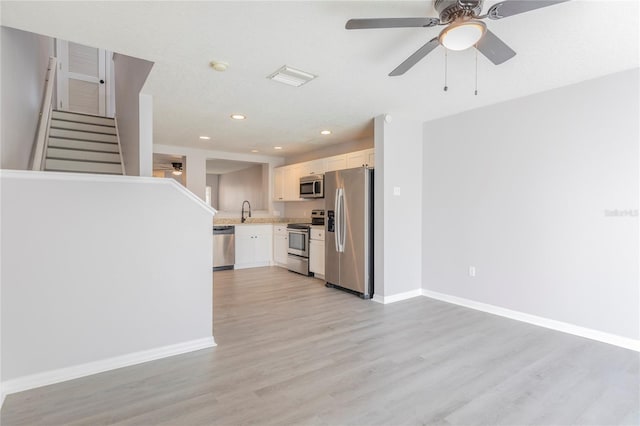 kitchen with white cabinetry, stainless steel appliances, ceiling fan, light hardwood / wood-style flooring, and sink