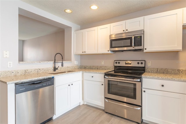 kitchen with a textured ceiling, sink, stainless steel appliances, and white cabinets