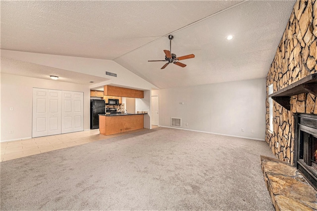 unfurnished living room featuring a fireplace, a textured ceiling, lofted ceiling, ceiling fan, and light carpet