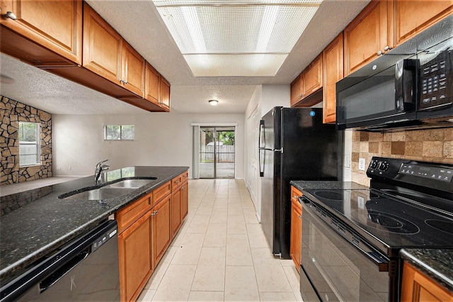 kitchen with a textured ceiling, dark stone counters, sink, and black appliances