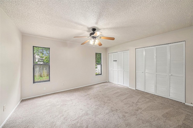 unfurnished bedroom with multiple windows, ceiling fan, and light colored carpet