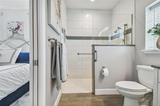 bathroom with wood-type flooring, toilet, and tiled shower