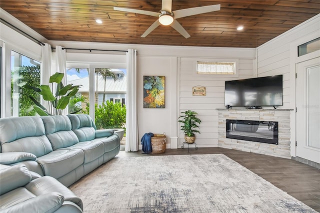 living room featuring wood ceiling, dark wood-type flooring, a stone fireplace, wood walls, and ceiling fan