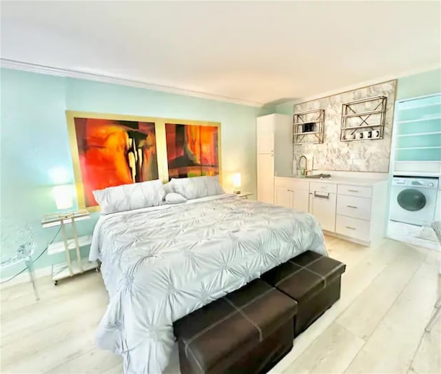 bedroom with ornamental molding, light hardwood / wood-style flooring, and washer / clothes dryer