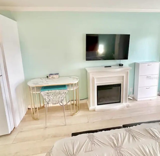 living room featuring a glass covered fireplace, wood finished floors, and ornamental molding