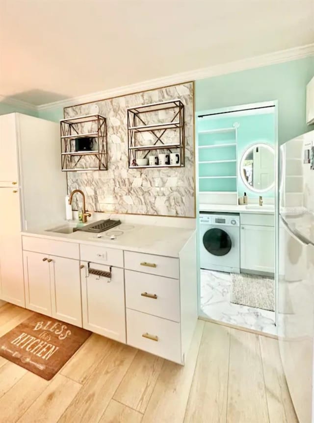 kitchen featuring light hardwood / wood-style flooring, washer / clothes dryer, crown molding, sink, and white cabinets