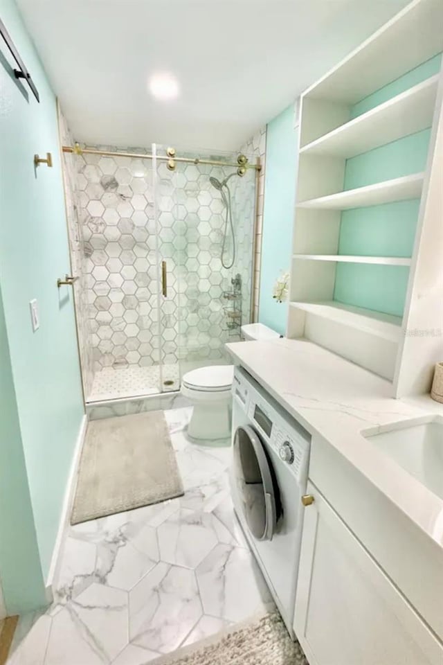 bathroom featuring marble finish floor, toilet, vanity, a stall shower, and washer / clothes dryer