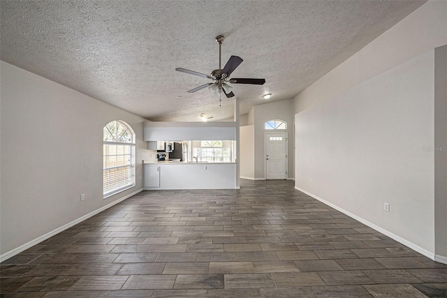 unfurnished living room with a textured ceiling, lofted ceiling, dark wood-type flooring, and ceiling fan