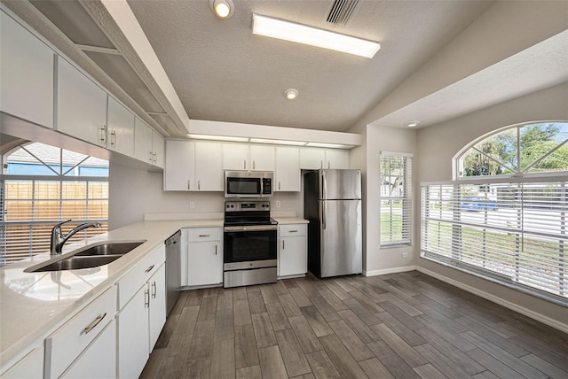 kitchen featuring stainless steel appliances, dark wood-type flooring, sink, and white cabinetry