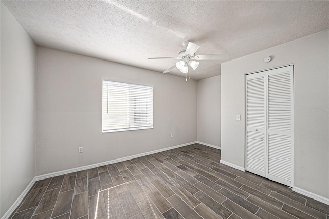 unfurnished bedroom with ceiling fan, a textured ceiling, a closet, and dark hardwood / wood-style floors