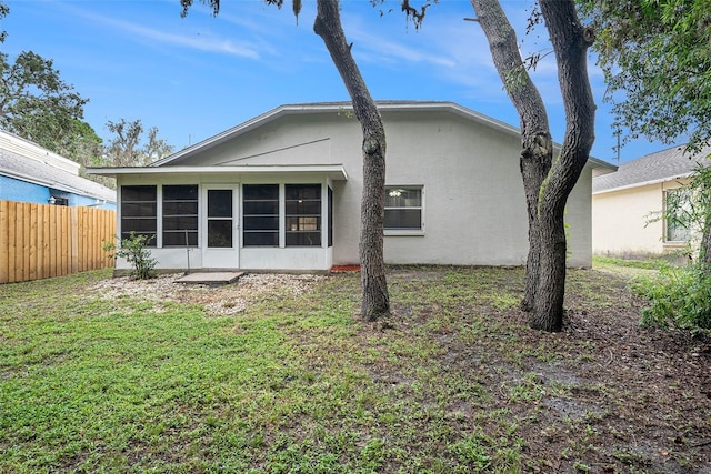 rear view of property featuring a lawn and a sunroom