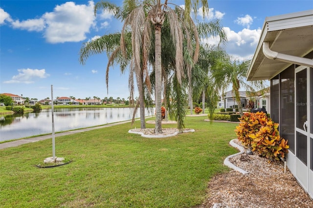 view of yard with a sunroom and a water view