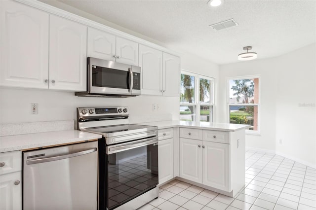 kitchen with white cabinets, stainless steel appliances, a textured ceiling, and light tile patterned flooring