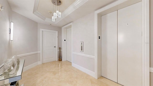 corridor with crown molding, elevator, an inviting chandelier, and a raised ceiling