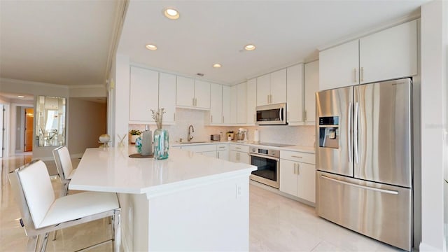 kitchen featuring white cabinets, a kitchen breakfast bar, sink, crown molding, and stainless steel appliances