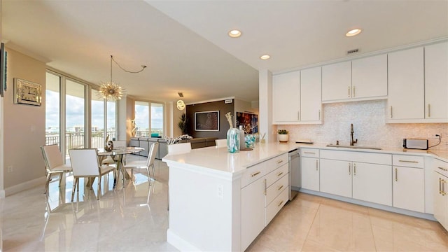 kitchen featuring decorative backsplash, dishwasher, kitchen peninsula, sink, and white cabinetry