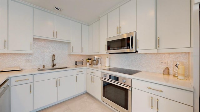 kitchen with appliances with stainless steel finishes, decorative backsplash, white cabinets, and sink