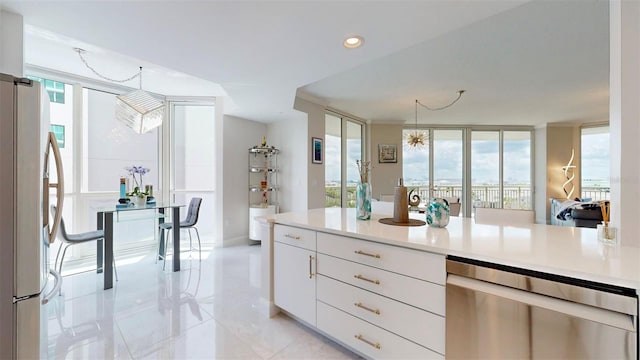 kitchen with white cabinetry, decorative light fixtures, fridge, and plenty of natural light