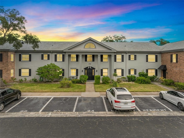 exterior space with uncovered parking, a lawn, and stucco siding