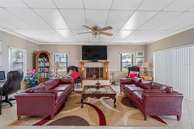 living room with crown molding, a drop ceiling, and light tile patterned floors