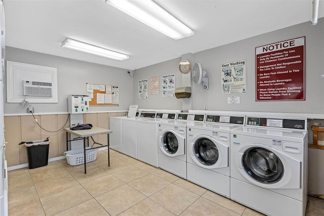 clothes washing area with washer and clothes dryer, light tile patterned flooring, and an AC wall unit