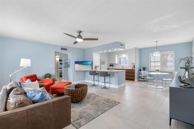 living area with baseboards, visible vents, and a ceiling fan